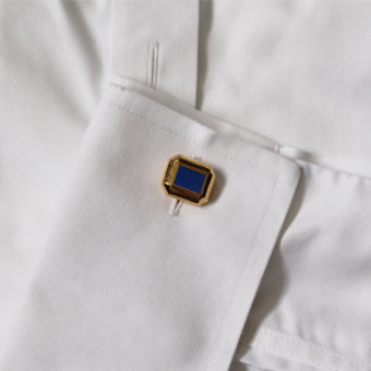 Gold cufflinks with blue enamel on shirt cuff